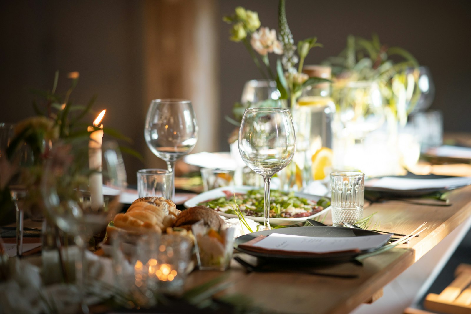 A rustic-elegant dinner table set with wine glasses and candlelight